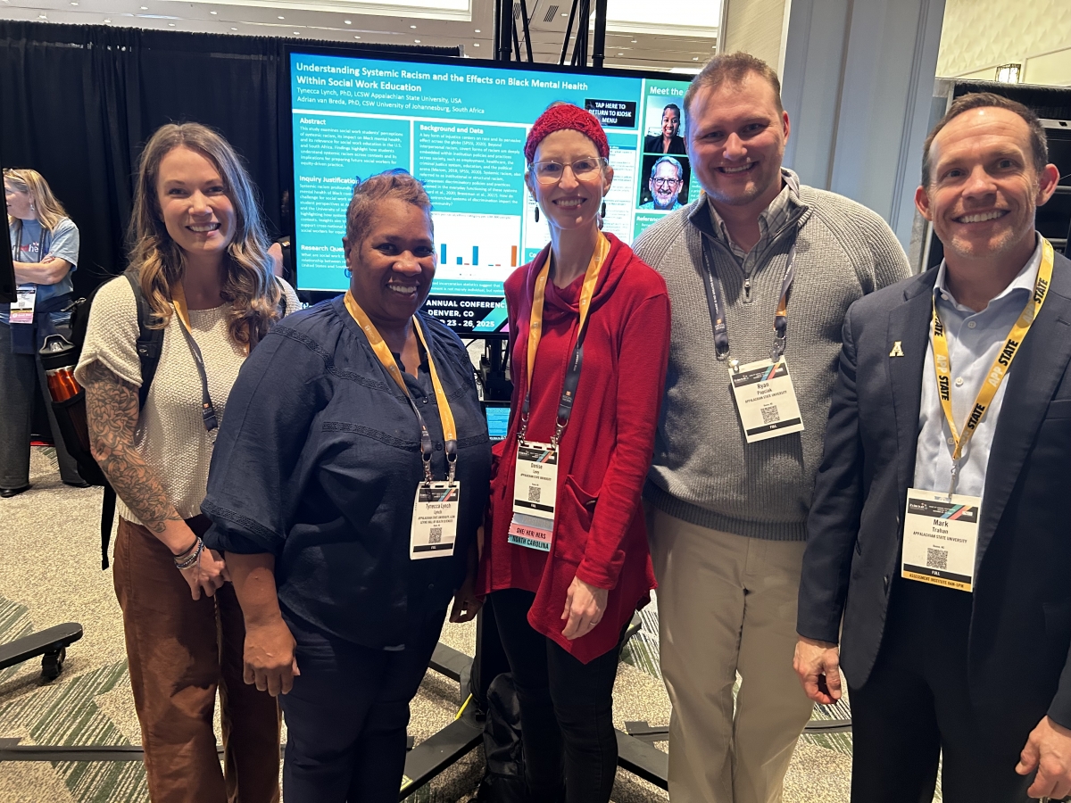 Faculty group photo in front of presentation screen